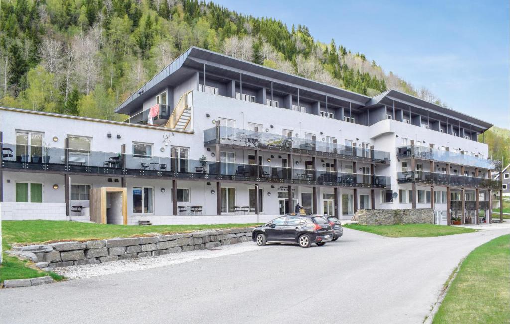 un grande edificio con un'auto parcheggiata di fronte di Nice Apartment In Vossestrand With Swimming Pool a Vossestrand