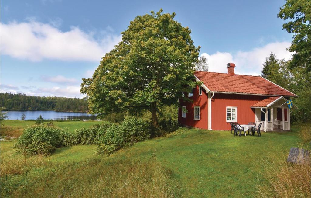una casa roja en un campo de hierba junto a un árbol en Amazing Home In Hedekas With Kitchen, en Kåtebol