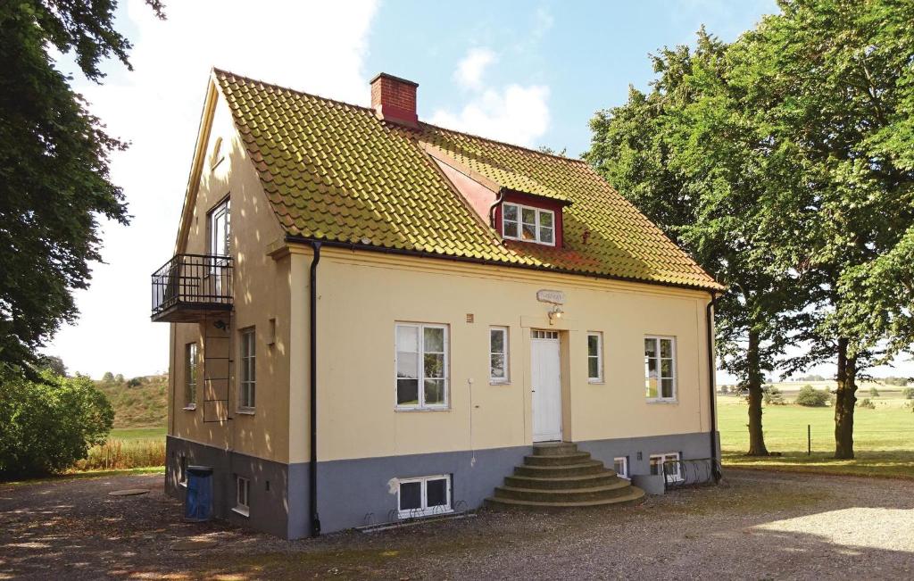 a small yellow house with stairs in a yard at Amazing Home In Tomelilla With Kitchen in Bollerup
