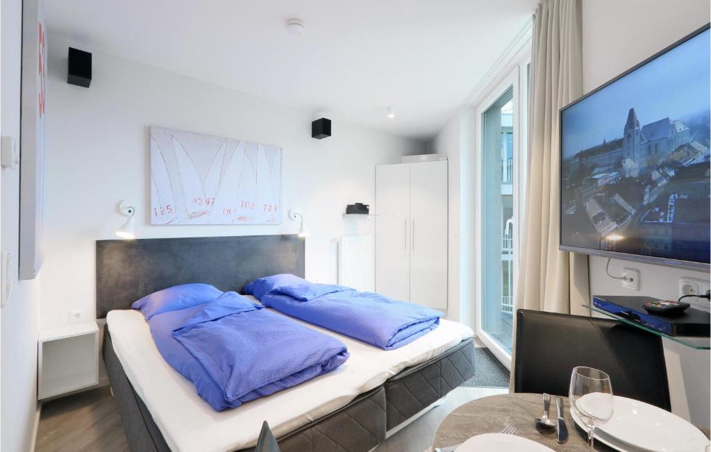 a bedroom with a bed with blue pillows and a tv at Dnenvilla Comfort in Travemünde