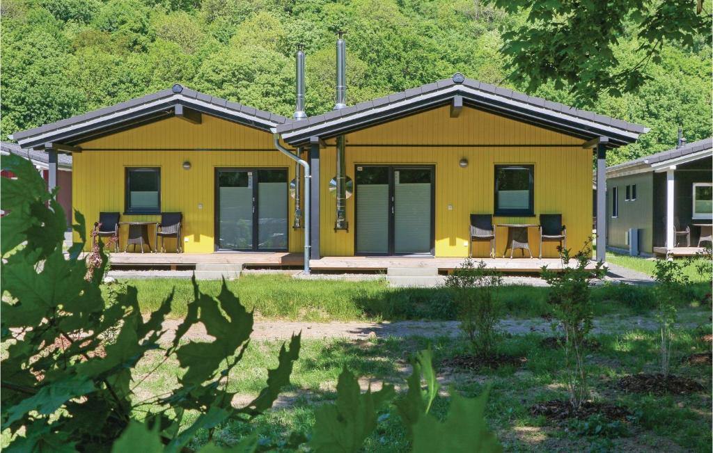 ein gelbes Haus mit Tischen und Stühlen in einem Hof in der Unterkunft Ferienhausdorf Thale in Thale