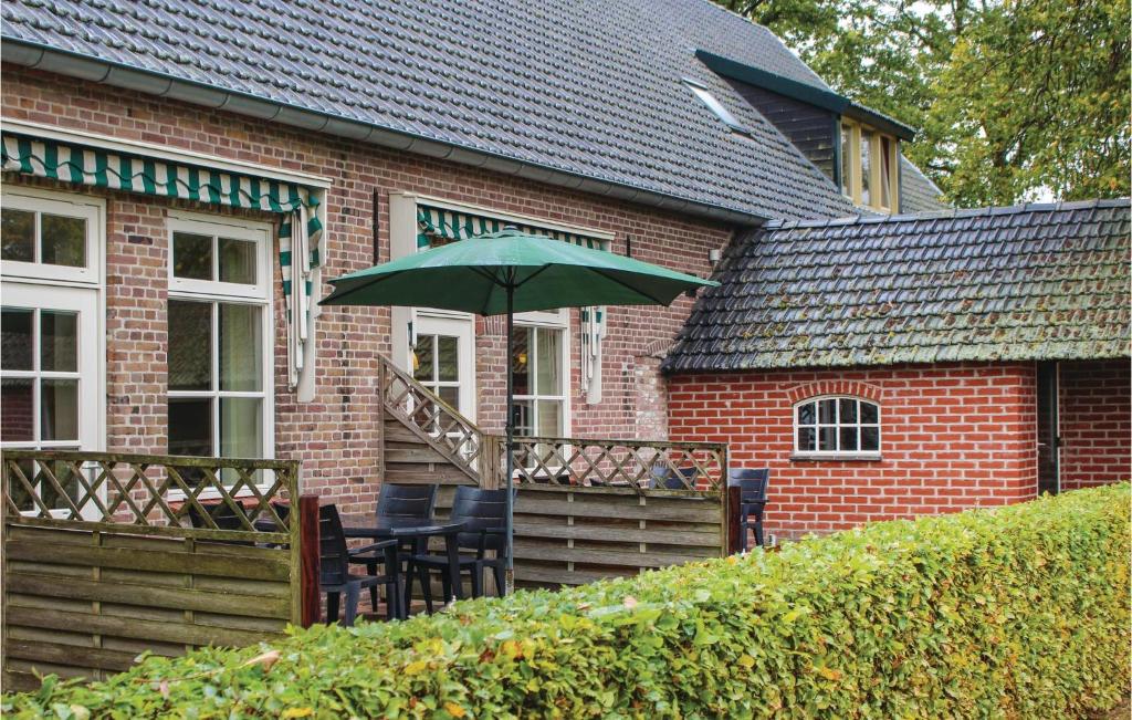 a table with a green umbrella in front of a house at Dorsvloer in De Moer