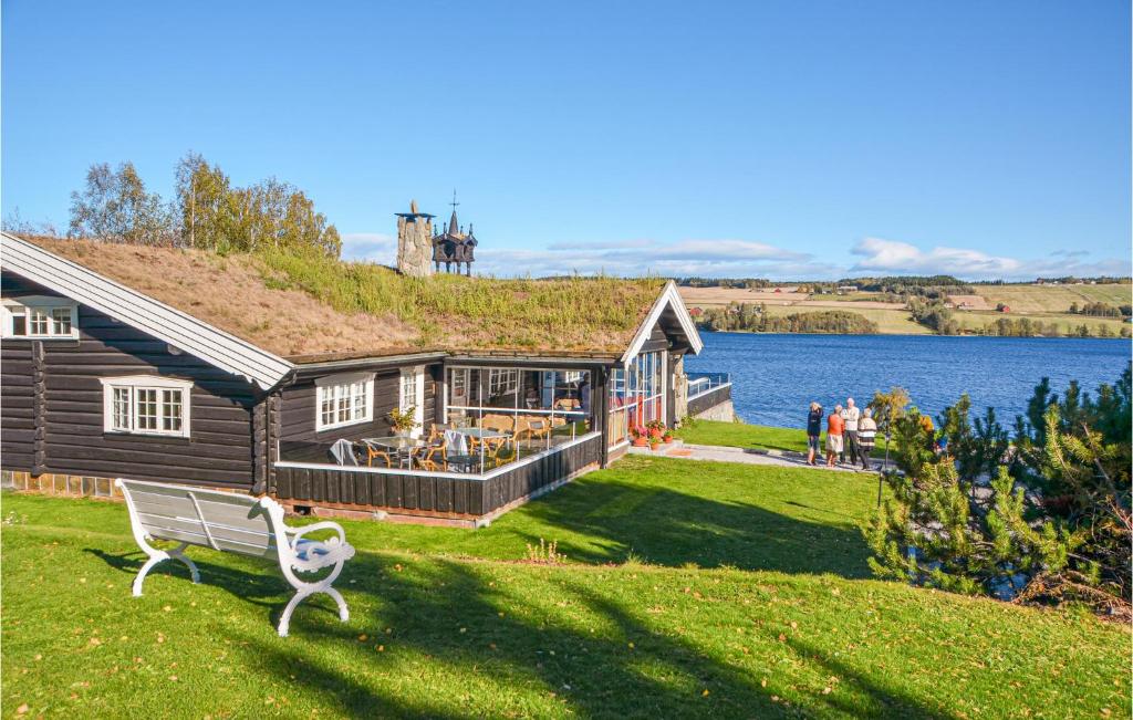 una casa con un banco en el césped junto a un lago en Bjrnslykkja en Eina