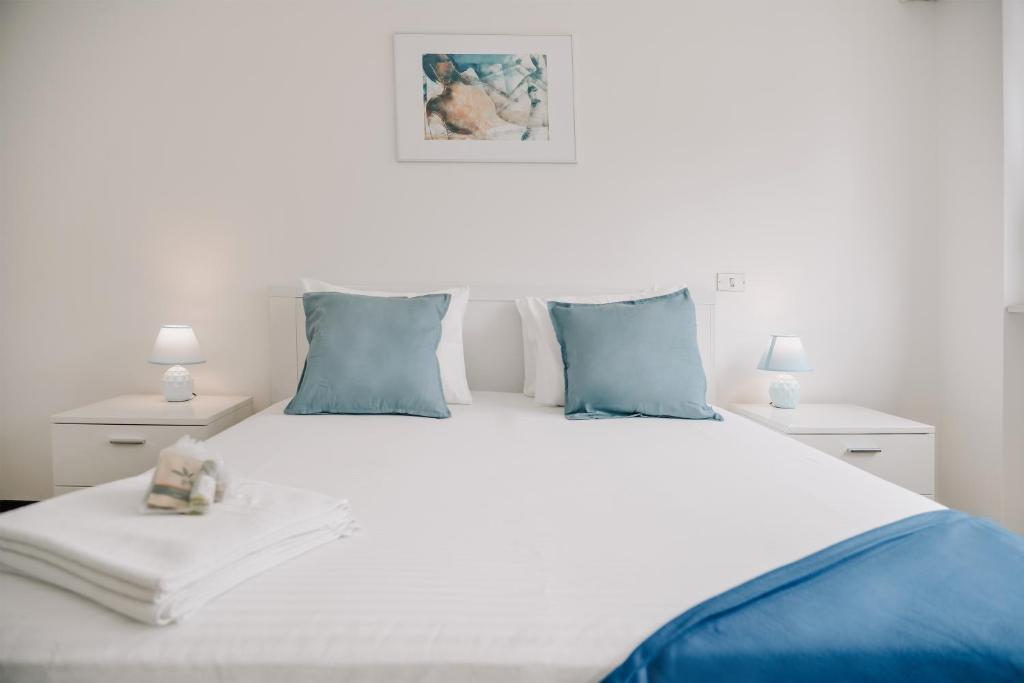 Una cama blanca con almohadas azules y un osito de peluche. en Lugano Central Suite Apartment Ciseri en Lugano