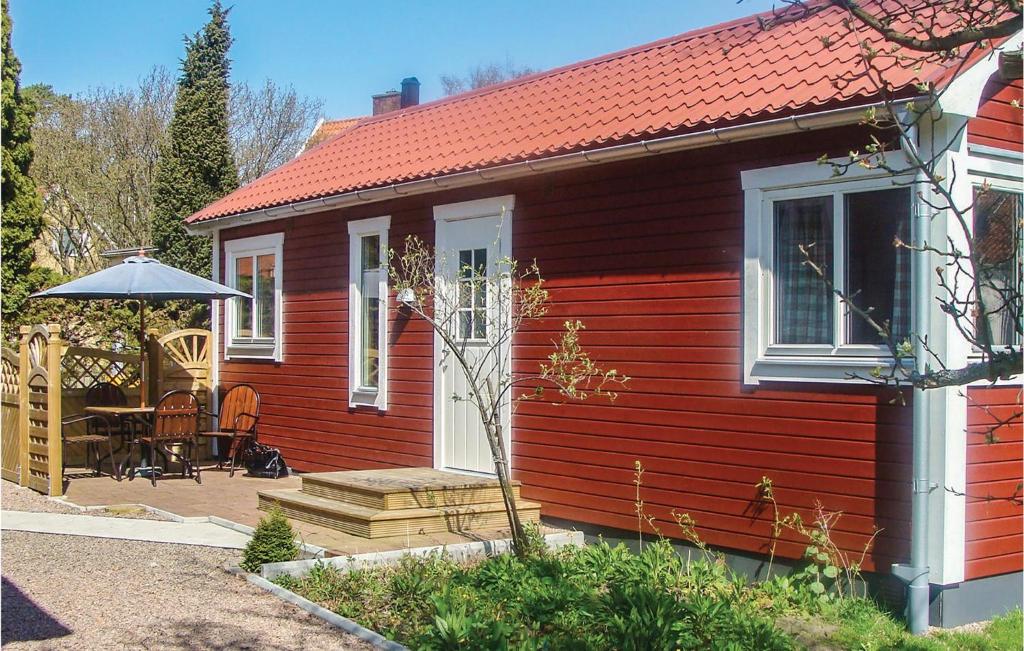 a red house with a table and an umbrella at Stunning Home In ngelholm With 1 Bedrooms in Ängelholm
