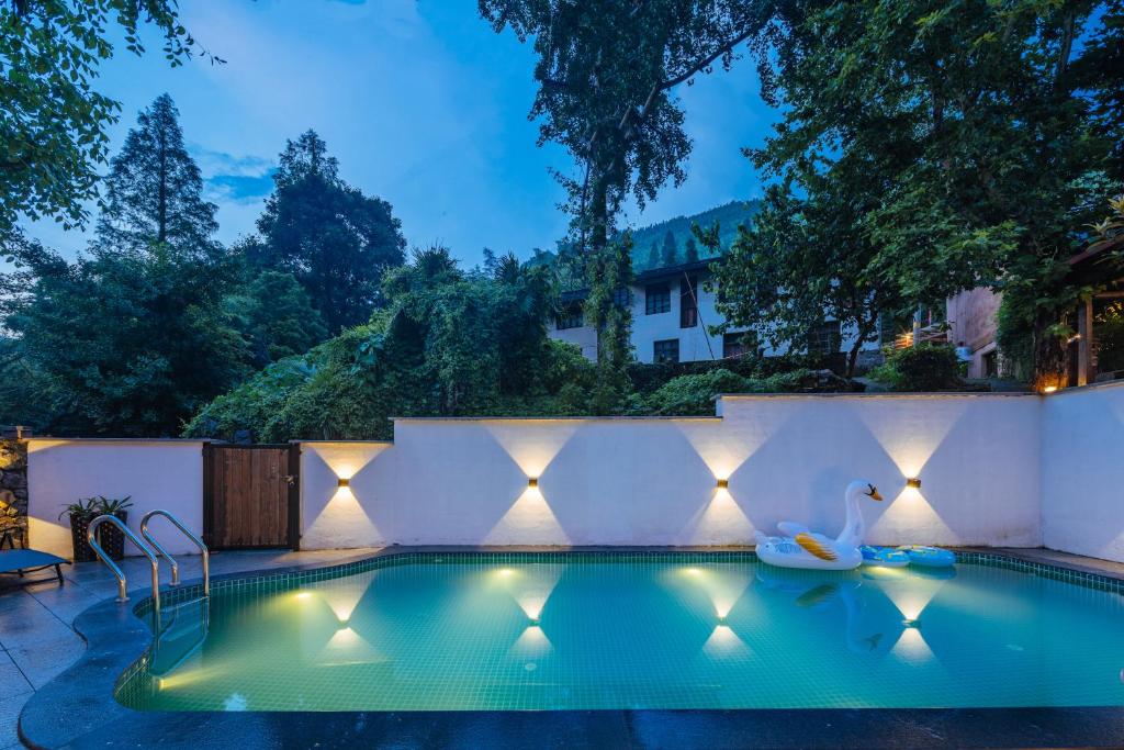 - une piscine éclairée dans un jardin la nuit dans l'établissement Moganshan Pinhouwu Hotel, à Deqing
