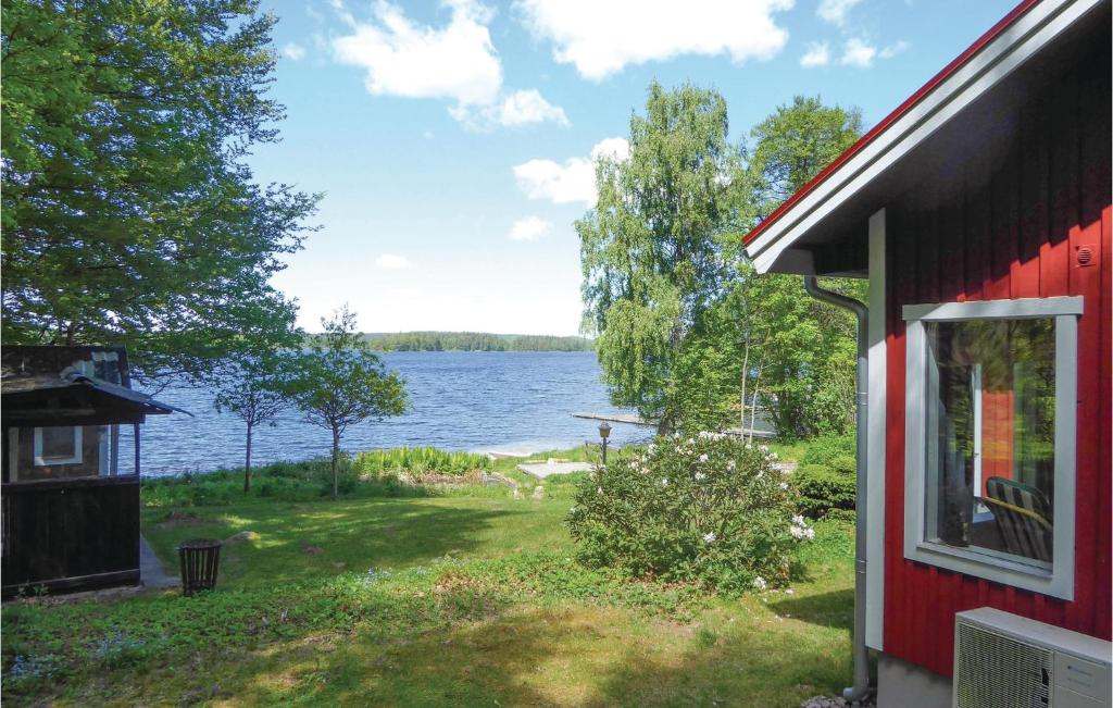 een rood huis met uitzicht op een meer bij Awesome Home In Arkelstorp With 2 Bedrooms in Immeln