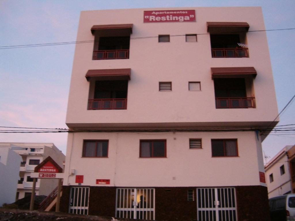 a white building with a red sign on it at Apartamentos Restinga in La Restinga