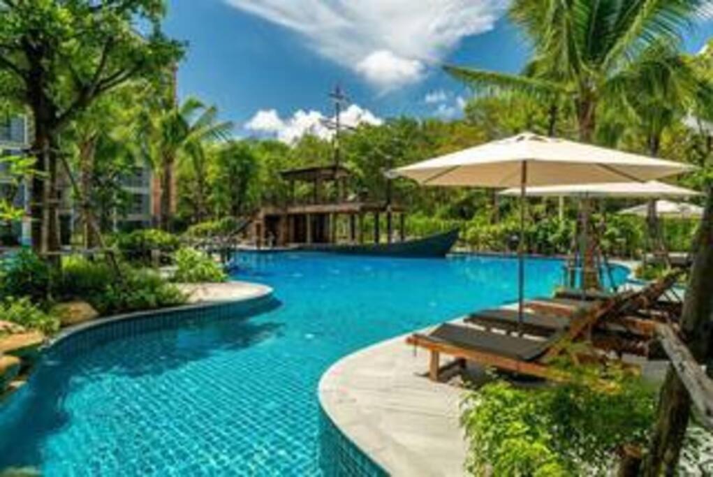a large swimming pool with chairs and an umbrella at Nayang Beach Brand New Executive Luxury Condo in Nai Yang Beach