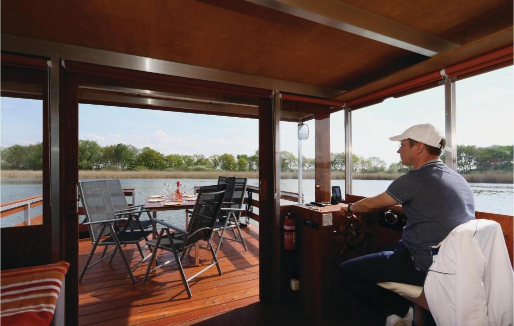 un homme assis sur le pont d'un bateau dans l'établissement Lovely Ship In Radewege With Kitchenette, à Radewege