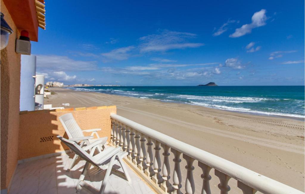 un balcón con 2 sillas blancas y una playa en Beautiful Home In Cartagena With Outdoor Swimming Pool, en Cartagena