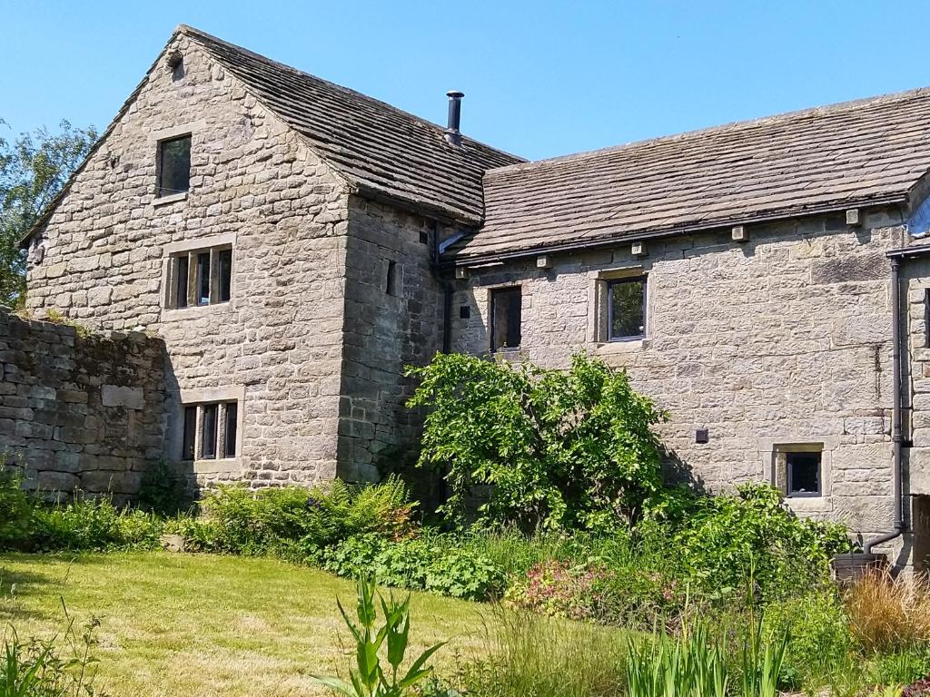 謝菲爾德的住宿－Wyndell Cruck Cottage，一座古老的石头建筑,前面有一个院子