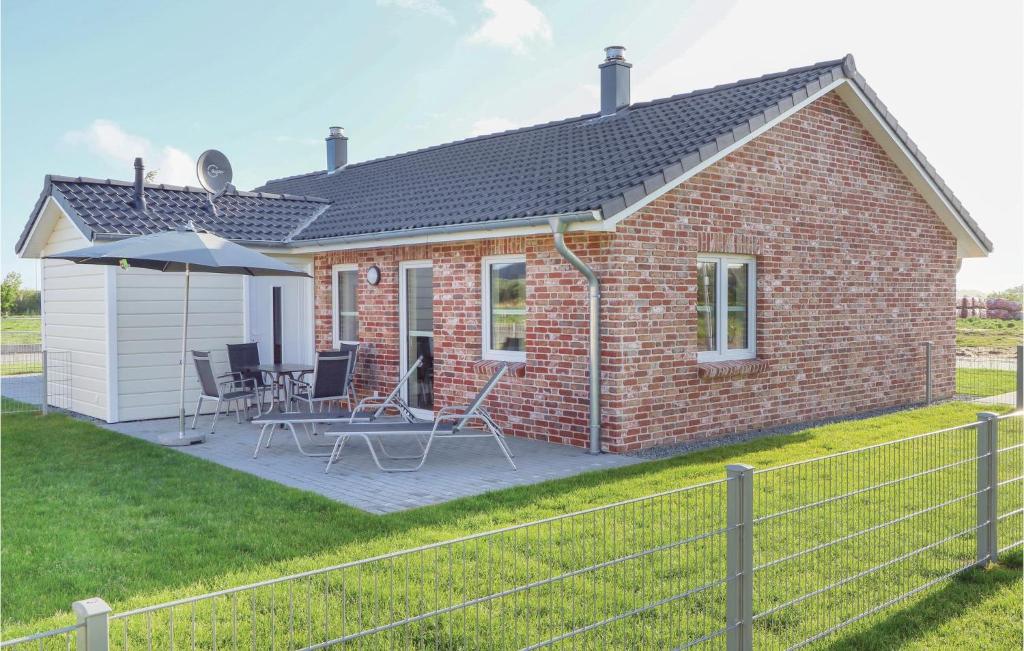 a brick house with a patio with chairs and an umbrella at 1 Bedroom Awesome Home In Dagebll in Dagebüll