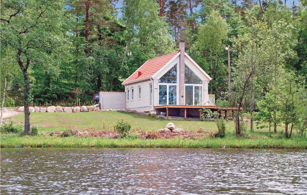 une petite maison avec un toit rouge à côté d'une masse d'eau dans l'établissement Cozy Home In sljunga With Kitchen, à Åsljunga