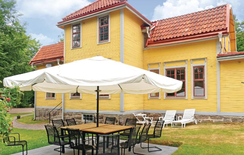 Svängsta的住宿－Cozy Home In Svngsta With Sauna，黄色房子前面带雨伞的桌子