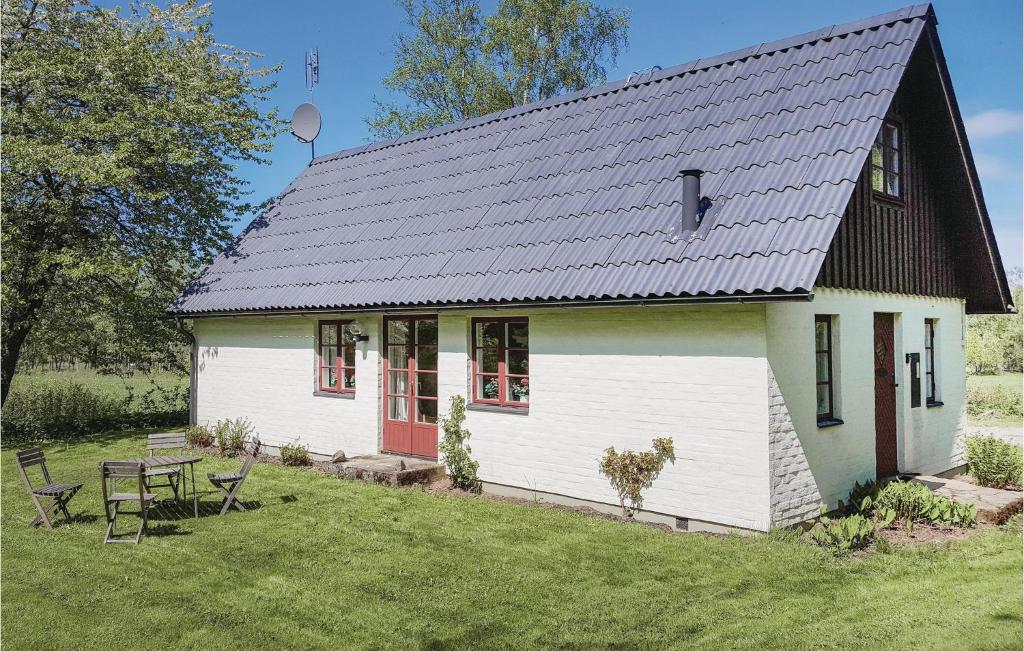 a small white house with a black roof at Nice Home In Bstad With 4 Bedrooms in Skottorp