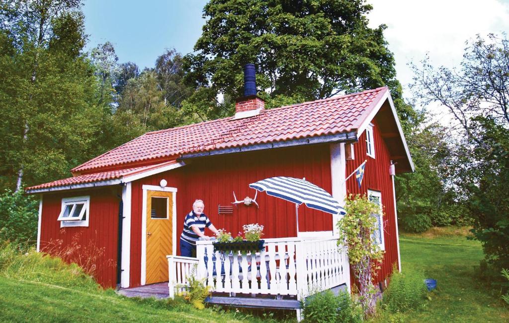 un homme debout à l'extérieur d'un hangar rouge avec un parapluie dans l'établissement Holiday Home Rådetorps Gård Storfors, à Rådetorp