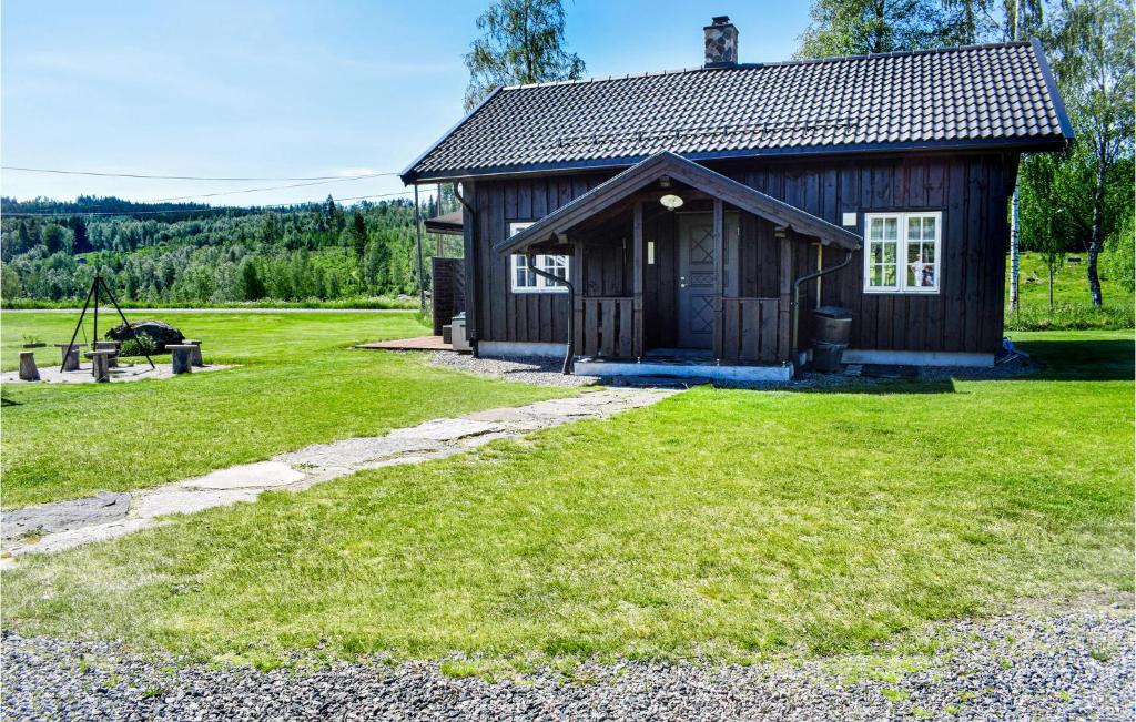 a small wooden cabin with a grass yard at One-Bedroom Holiday Home In Austmarka in Östmarken