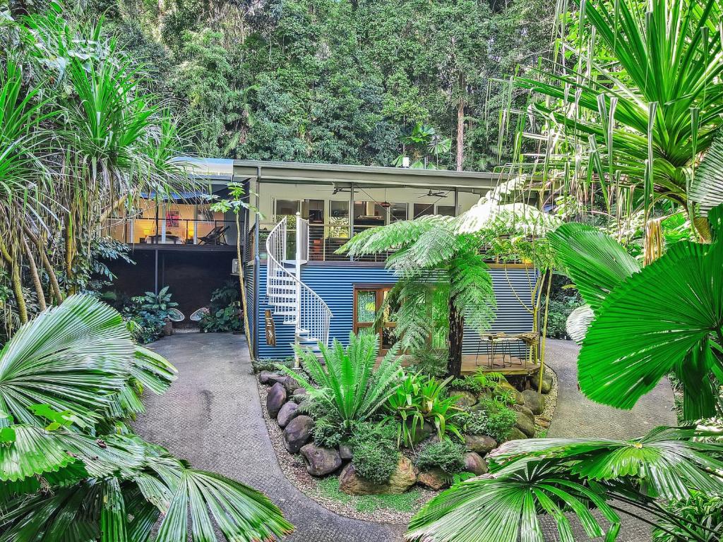 a blue house in the middle of some trees at Villa Vihara Rainforest Penthouse in Innisfail