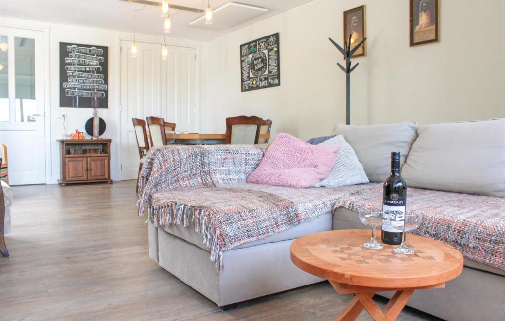 Sala de estar con sofá y mesa con botella de vino en Te Warskip en Andijk