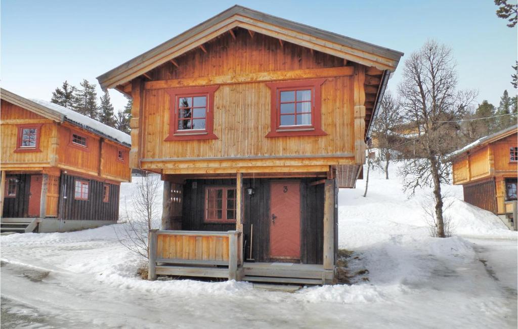 a wooden cabin with a red door in the snow at Lovely Home In Ringebu With Kitchen in Odlo