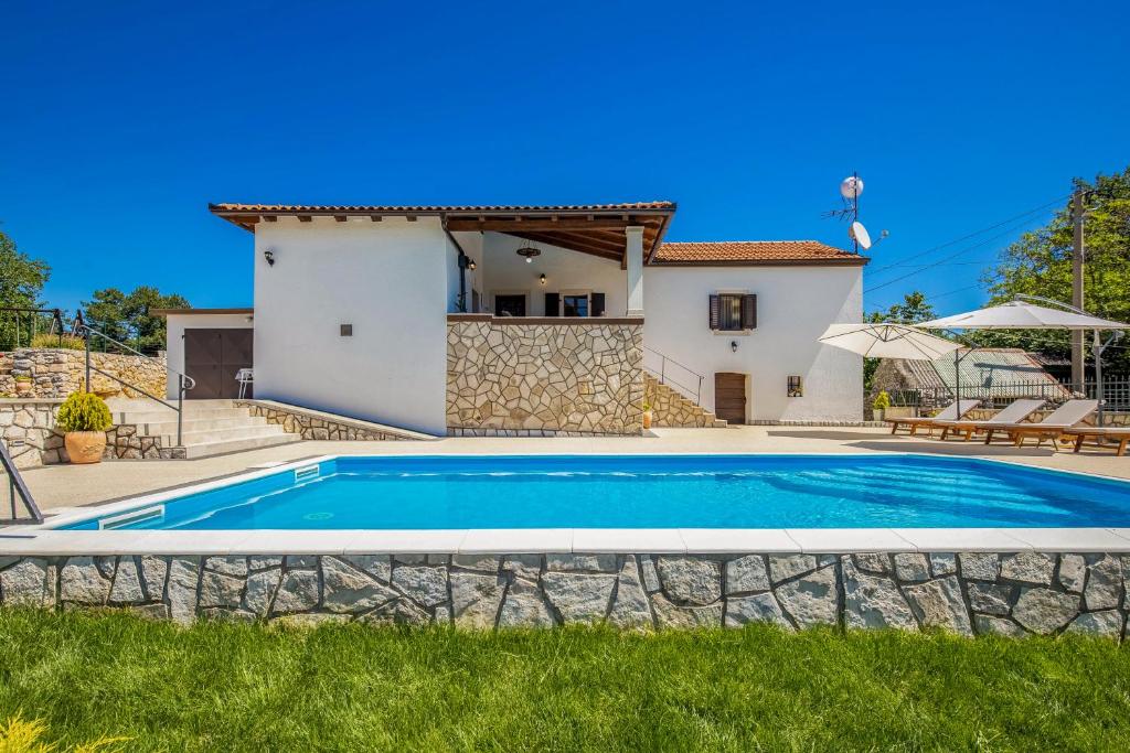 a villa with a swimming pool in front of a house at Villa Simici quiet peaceful place with pool perfect to enjoy the nature in Mošćenička Draga