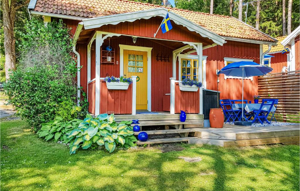 a red house with a yellow door and a table and an umbrella at Pet Friendly Home In Sollebrunn With Wifi in Sollebrunn