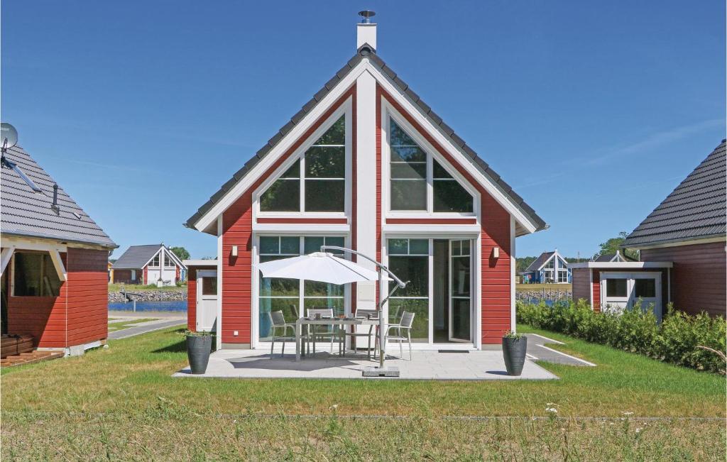 une maison rouge avec une table et un parasol dans l'établissement Cozy Home In Zerpenschleuse With Wifi, à Zerpenschleuse