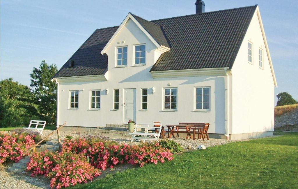 a white house with a table and chairs and flowers at 3 Bedroom Awesome Home In Ystad in Ystad