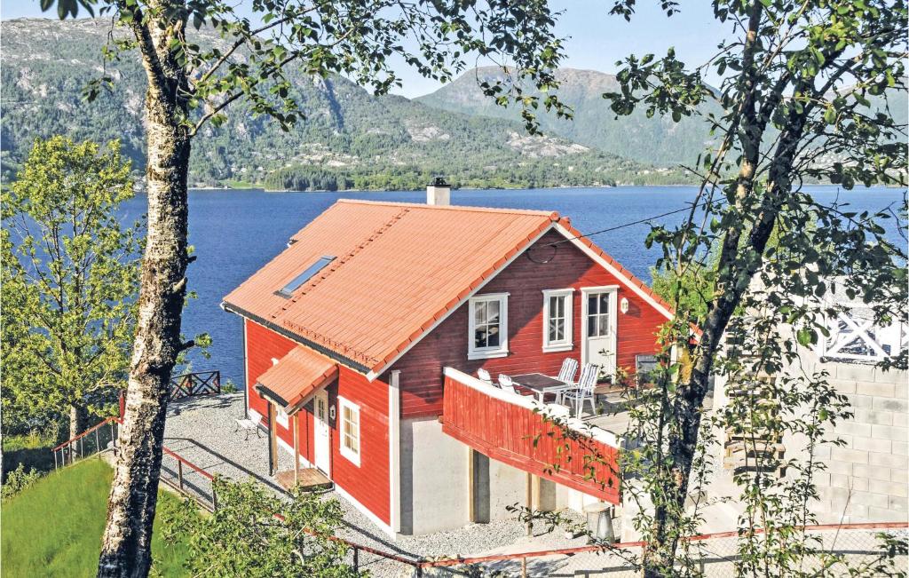 uma casa vermelha com um telhado laranja ao lado de um lago em Nice Home In Vaksdal With House A Mountain View em Stavenesli