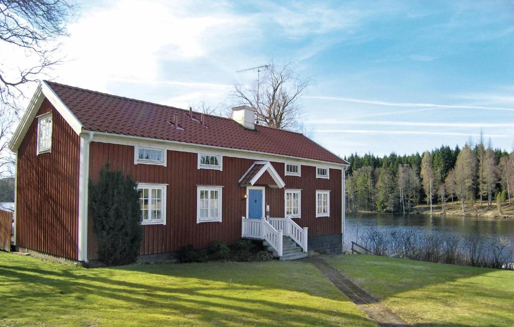 a red house with a white door and a lake at 4 Bedroom Nice Home In Bottnaryd in Bottnaryd