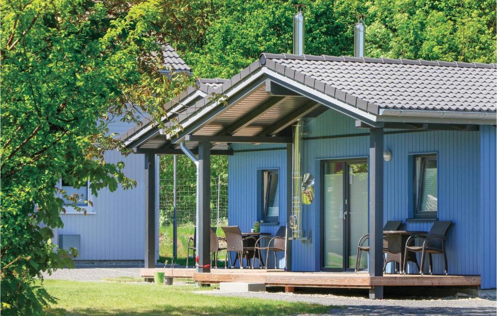 une maison bleue avec une terrasse en bois et des chaises dans l'établissement Ferienhausdorf Thale, à Thale