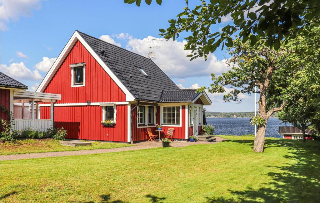 a red house with a lake in the background at Nice Home In Trans With Kitchen in Tranås