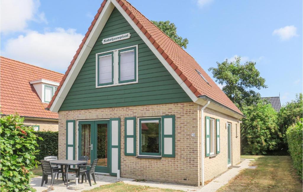 uma pequena casa com um telhado verde e uma mesa em Awesome Home In Zonnemaire With 3 Bedrooms And Wifi em Zonnemaire