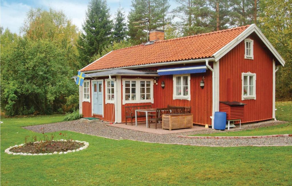 una casa roja con una mesa en el patio en Lovely Home In Bjrnlunda With Kitchen, en Åttersta