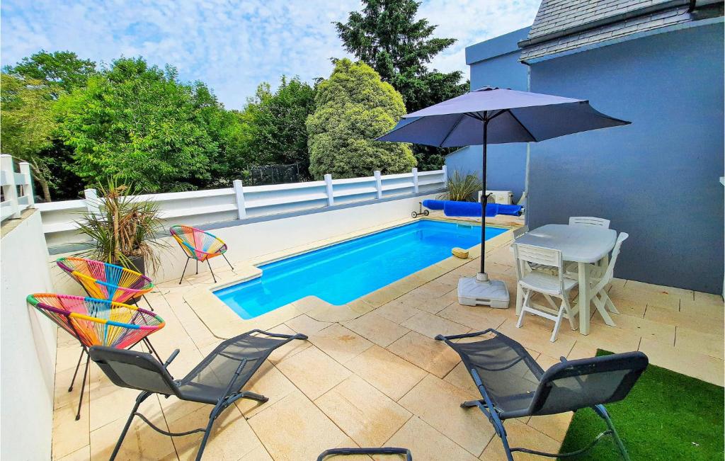 un patio con mesa, sillas y sombrilla en Lovely Home In La Fort Fouesnant With Private Swimming Pool, Can Be Inside Or Outside, en La Forêt-Fouesnant