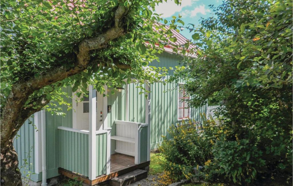 a green house with a white door and a tree at Beautiful Home In Jnkping With 1 Bedrooms in Jönköping