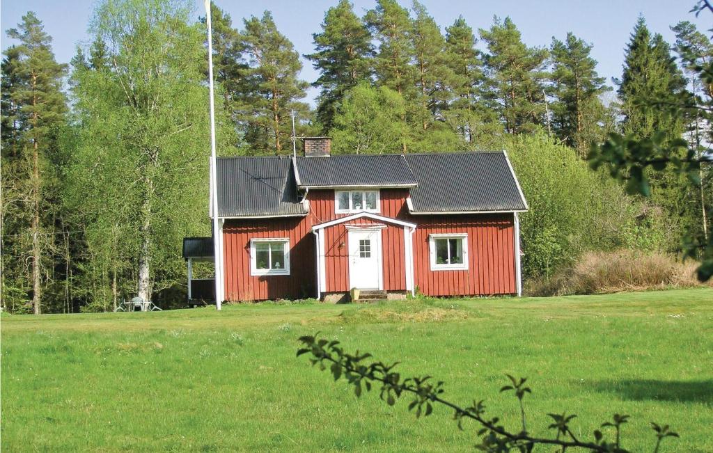 una casa rossa con un tetto nero in un campo di Gorgeous Home In Lngaryd With Kitchen a Långaryd