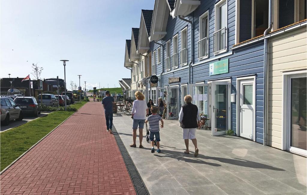 a family walking down a sidewalk in front of a building at Lovely Studio In Dagebll With Kitchenette in Dagebüll