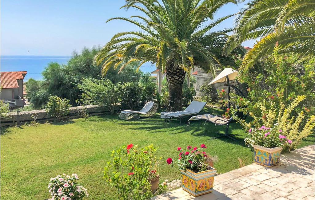 濱海布蘭卡列翁涅的住宿－Pet Friendly Home In Brancaleone With House Sea View，一个带椅子和棕榈树的花园以及大海