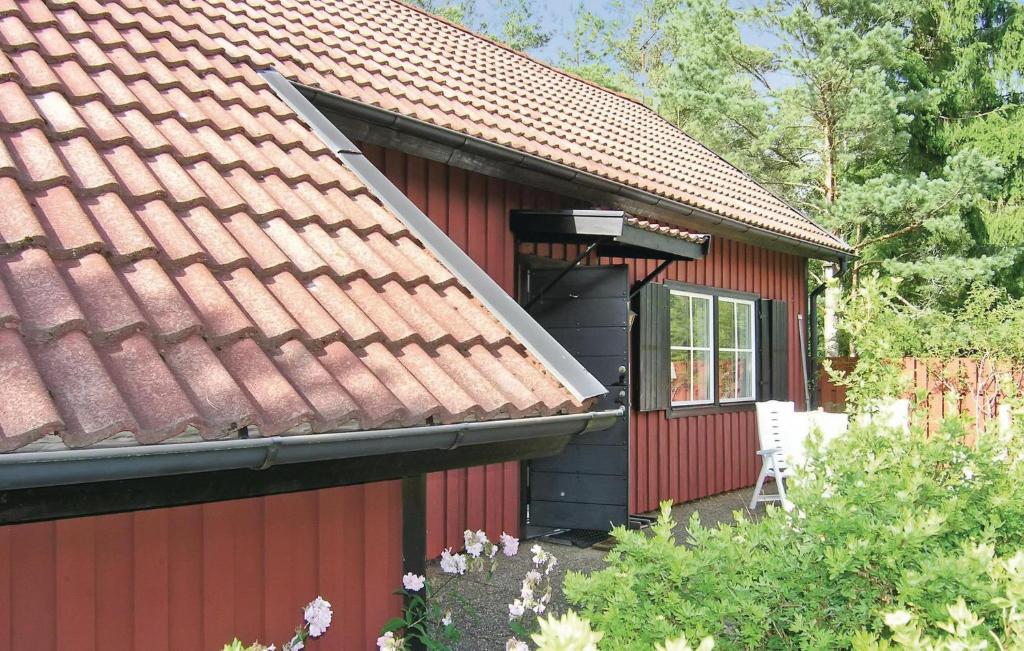 una casa rossa con tetto rosso e sedia bianca di Stunning Home In Hestra With Sauna a Hestra
