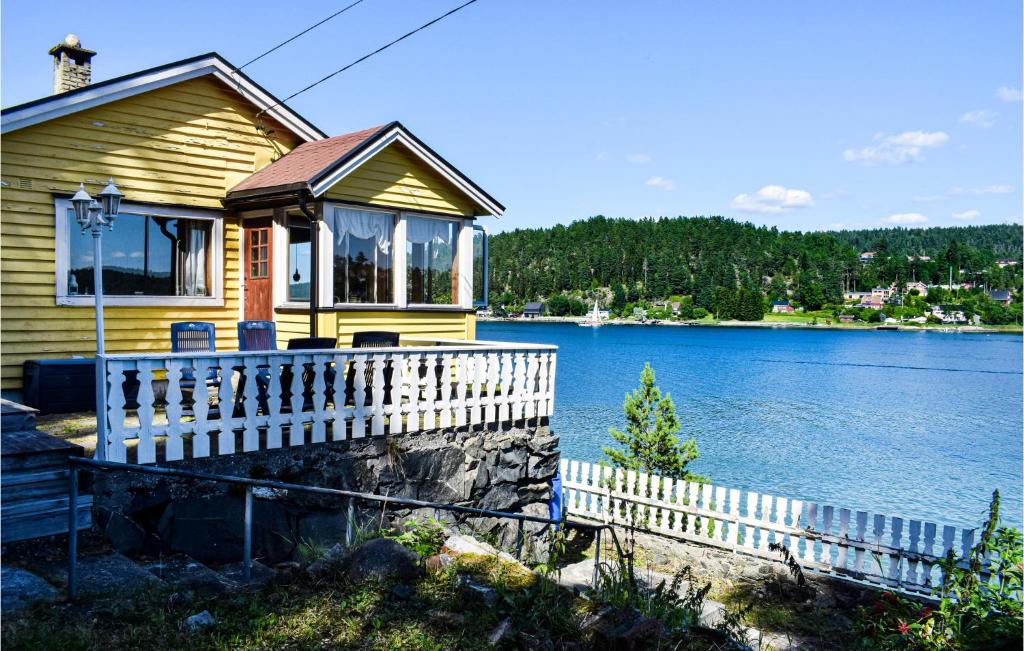 a yellow house on the shore of a lake at Beautiful Home In Nordre Frogn With 3 Bedrooms in Brevik