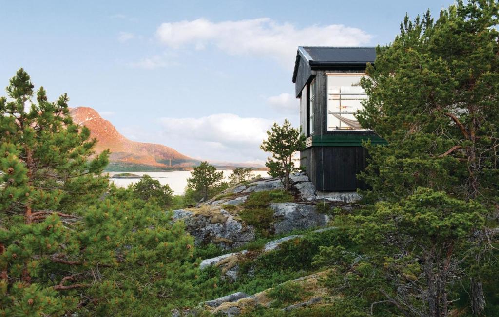 a small house on top of a hill with trees at Awesome Home In Ballangen With Kitchen in Langvåg