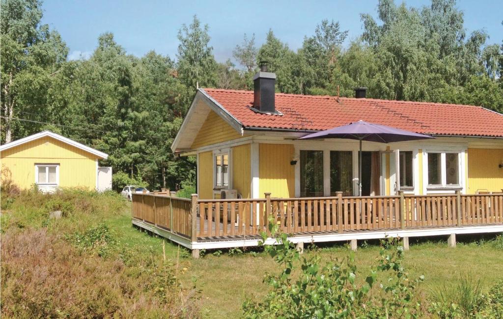 a yellow house with a deck and an umbrella at Beautiful Home In Ljusterö With Kitchen in Laggarsvik