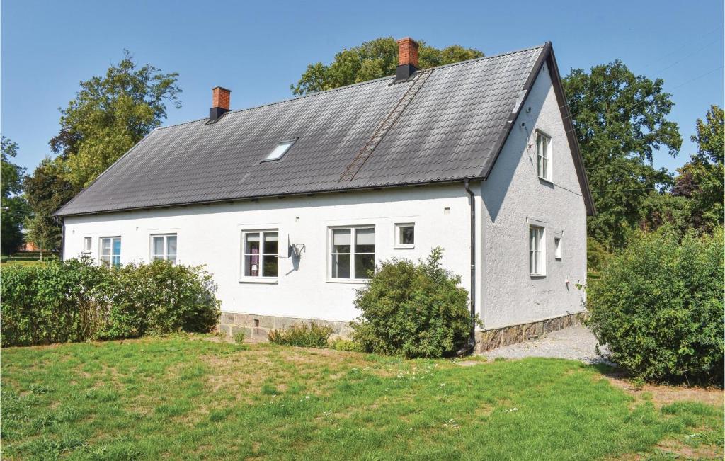 an old white house with a gray roof at Awesome Home In Tomelilla With Kitchen in Bollerup