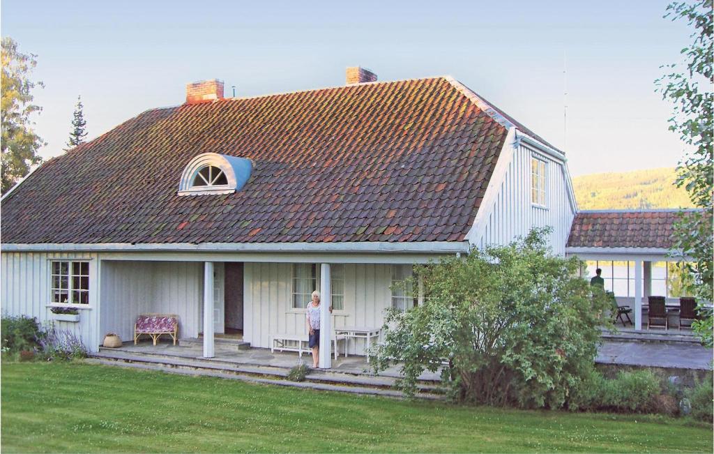 une femme debout sur la terrasse couverte d'une maison blanche dans l'établissement Gorgeous Home In Vestsida With House Sea View, à Hov