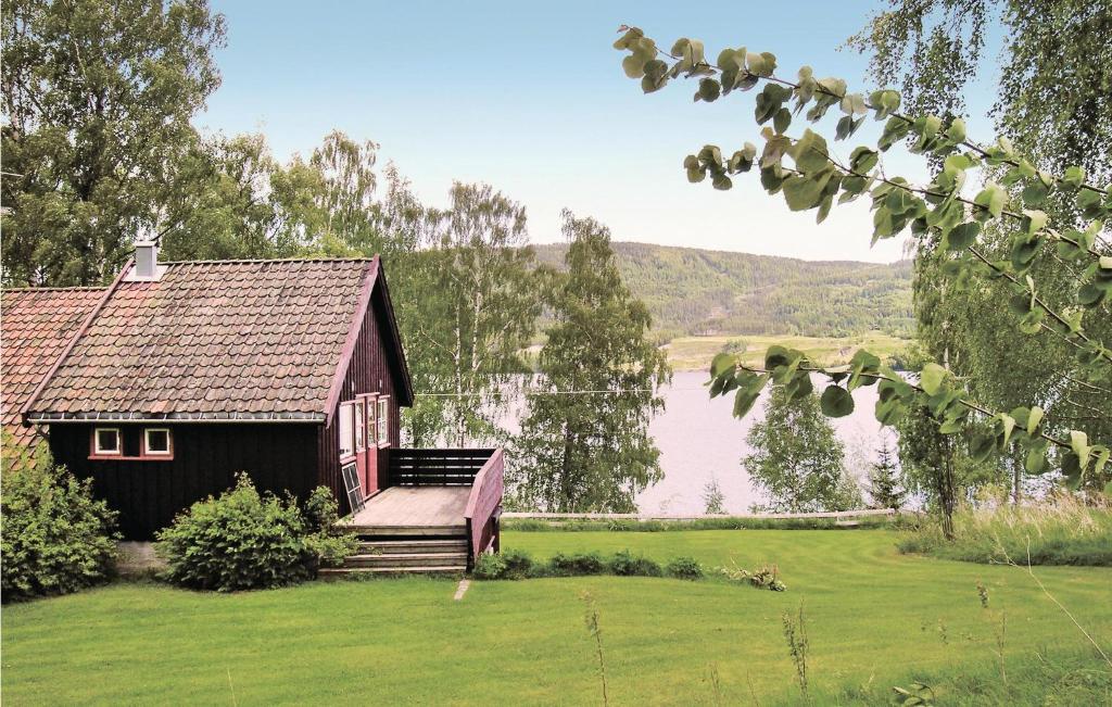 a small house on a lawn next to a lake at Lovely Home In Vestsida With Wifi in Hov