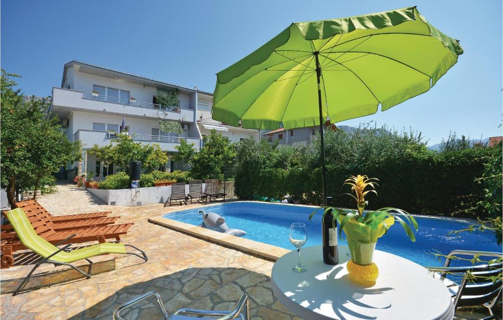 a table with a green umbrella next to a pool at 1 Bedroom Nice Apartment In Kastel Sucurac in Kaštela