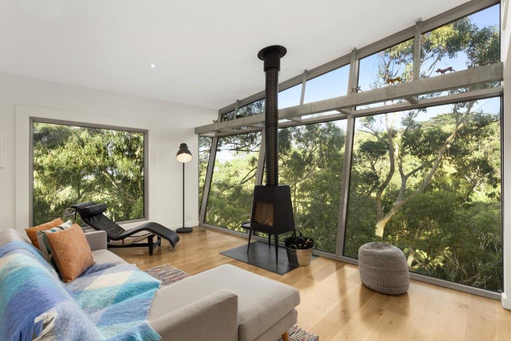 a living room with a fireplace and large windows at Bungoona in Apollo Bay