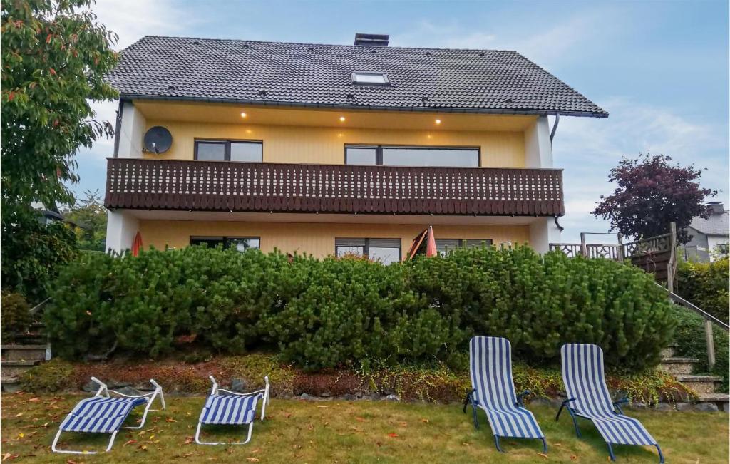 メーデバッハにあるCozy Apartment In Medebach-ddinghausen With Kitchenの家の前に三脚の芝生の椅子がある家